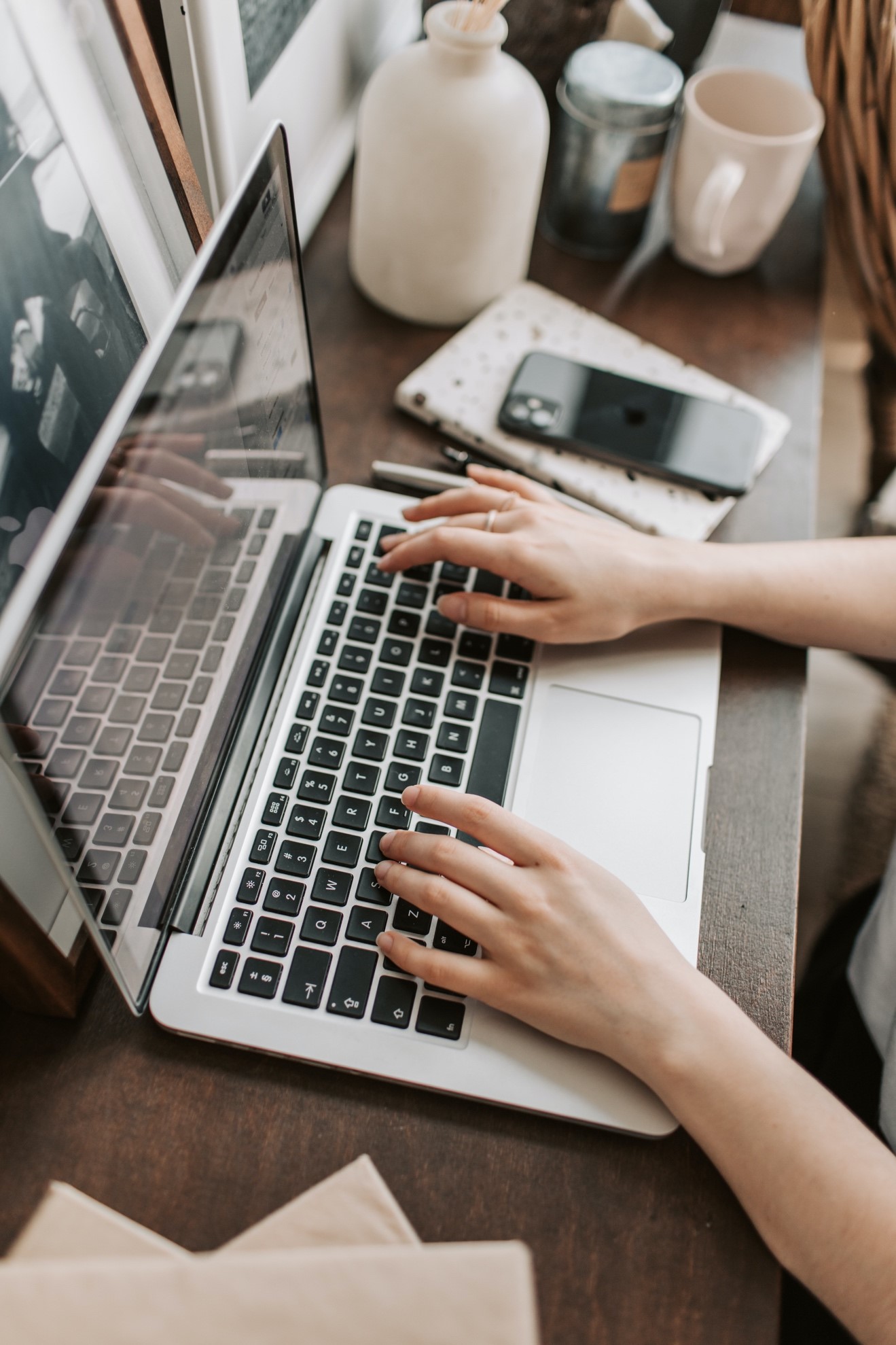 Someone using multiple connected devices, a laptop and phone, requiring the greater Internet speed and bandwidth of Fiber Internet